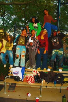 a group of young people standing on top of a wooden bench next to each other