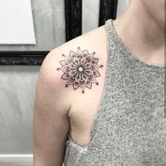 a woman with a tattoo on her shoulder has a black and white flower in the center