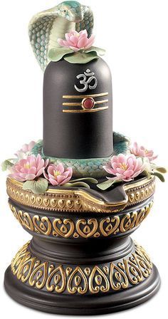 a black and gold vase with pink flowers on the top is sitting on a pedestal