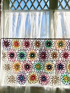 the curtain is decorated with colorful crochet doily and has flowers on it