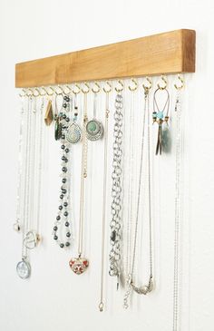 a wooden rack with many different necklaces hanging from it's sides and attached to the wall