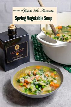 a bowl of vegetable soup next to a bottle of wine