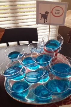 there are many cups that have blue liquid in them on the table with a sign