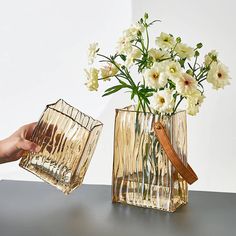 two clear vases with white flowers in them on a table next to each other