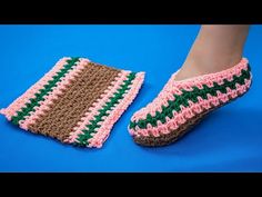 a pair of crocheted slippers sitting on top of a blue floor next to a woman's foot