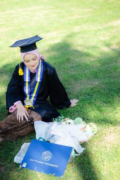 a woman sitting on the ground wearing a graduation cap and gown