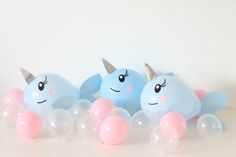 three balloons with unicorn faces are lined up on a table