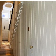 a cat is sitting on the floor next to a stair case in a house with white walls