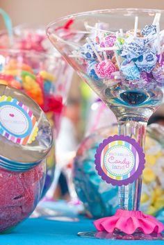 there are many candies in glass bowls on the table with candy sticks and lollipops