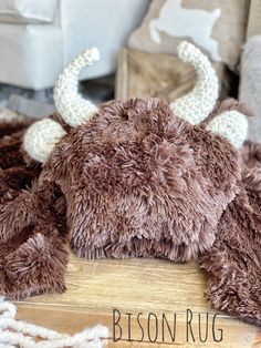 a stuffed animal that is laying down on the floor next to a wooden sign reading bison rug