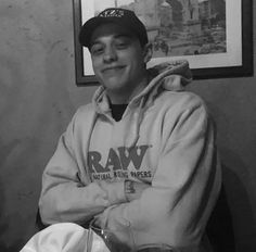 a black and white photo of a man wearing a hoodie with his arms crossed