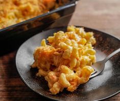 a black plate topped with macaroni and cheese next to a casserole dish