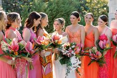 a group of women standing next to each other in dresses and holding bouquets together