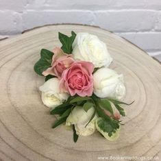 white and pink flowers sitting on top of a wooden table