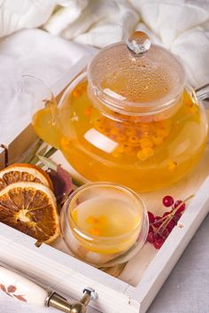 a tea pot filled with liquid next to sliced oranges