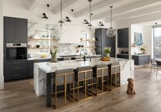 a large kitchen with marble counter tops and gold barstools in front of the island