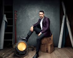 a man in a suit and tie sitting on a stool next to a light bulb