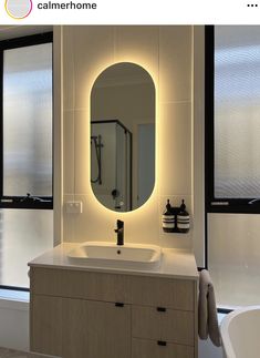 a bathroom with a sink, mirror and bathtub next to windows in the room