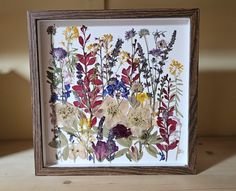 an image of flowers in a frame on a table