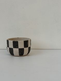 a black and white checkered bowl sitting on top of a table next to a wall