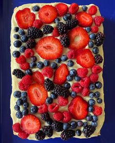 a cake with berries, blueberries and raspberries on top is sitting on a blue plate