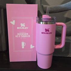 a pink travel mug sitting next to a cardboard box