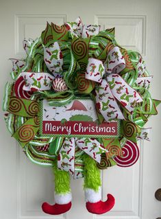 a christmas wreath hanging on a door with the words merry christmas written in red, green and white