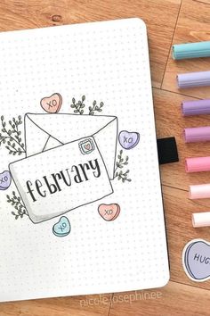 an open notebook with the word february written on it next to markers and pencils