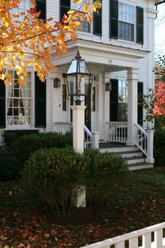 a white house with black shutters on the front porch and steps leading up to it