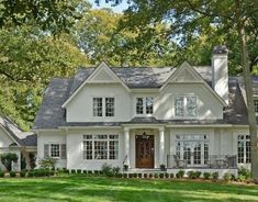 a large white house with lots of windows and grass in front of the door is surrounded by trees