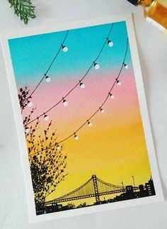 an image of a card with string lights and a bridge in the background at sunset