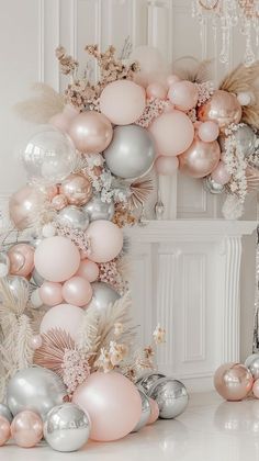 a bunch of balloons that are in the air next to some flowers and feathers on a table