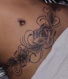 a woman's stomach with a rose tattoo on it and flowers around the side