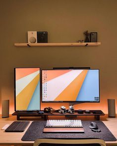 two computer monitors sitting on top of a wooden desk