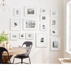 a dining room table and chairs in front of a wall with pictures hanging on it