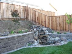 a stone wall next to a wooden fence