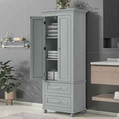 a bathroom with a gray cabinet next to a plant and toilet paper dispenser