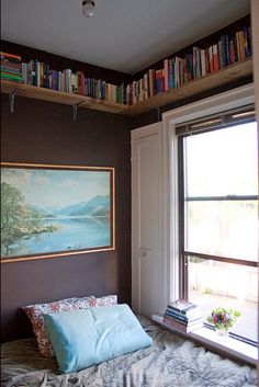 a bed sitting under a window next to a book shelf with books on top of it