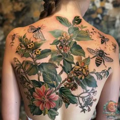 the back of a woman's body with flowers and bees tattooed on her chest