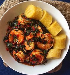 a white bowl filled with shrimp, spinach and pineapple slices on top of a blue table cloth