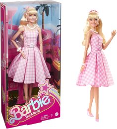 barbie doll in pink and white checkered dress next to cardboard box for barbie the movie