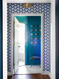 a room with blue and white wallpaper and a chair in the doorway to another room