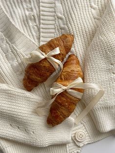 two croissants wrapped in white ribbon on top of a sweater