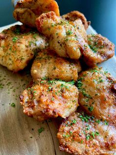 some chicken wings are on a plate with seasoning sprinkled around them and garnished with parsley