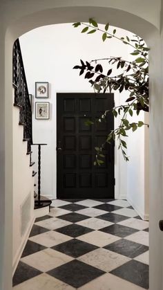 a black and white checkered floor with a door in the center is seen through an archway