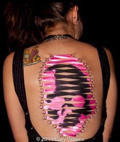 the back of a woman's body with pink and black designs on her chest