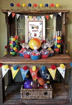 a birthday party with cupcakes, candy and decorations on a wooden table in front of a sign