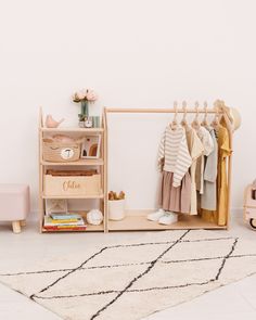 a wooden shelf with clothes hanging on it and a rug in the corner next to it