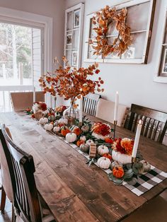 a dining room table decorated with pumpkins and greenery, candlesticks and flowers