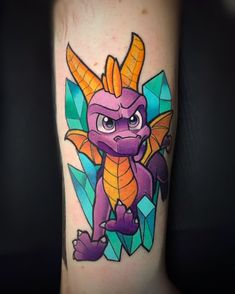 a tattoo with a purple dragon on it's arm and some green leaves around it